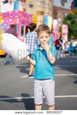 Cute kid eating cotton candy over fair background