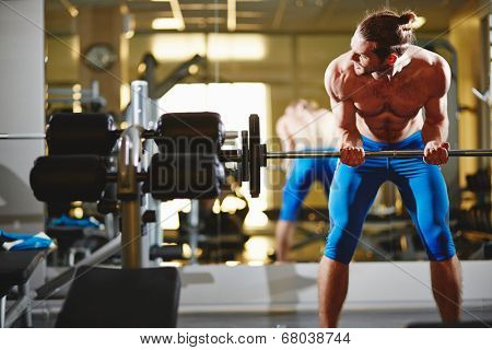 Portrait of sporty topless man lifting weight in gym 