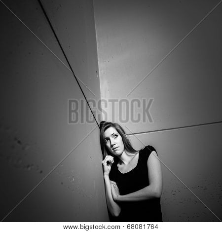 Young woman suffering from a severe depression (very harsh lighting is used on this shot to underline/convey the gloomy mood of the scene)
