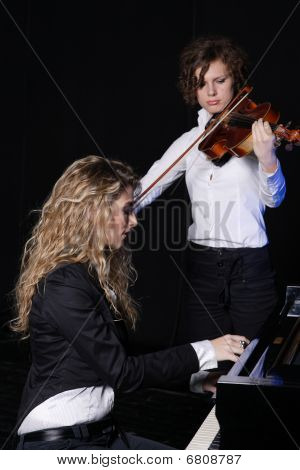Twee mooie jonge vrouwen poseren met viool en Piano