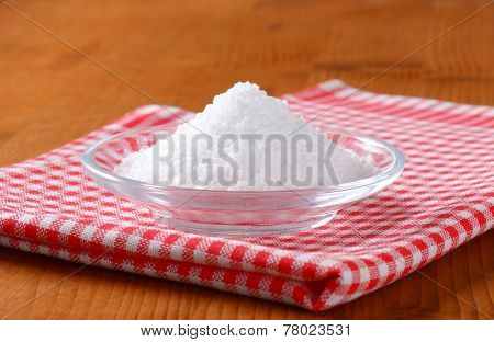heap of salt in the glass bowl with patterned napkin