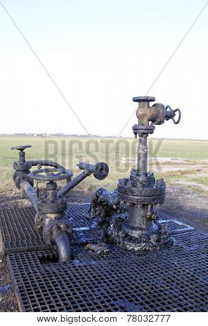 ARAD, ROMANIA - FRIDAY, DECEMBER 5, 2014: Oil leaks from a surface well head at a production field operated by OMV Petrom S.A, the largest gas and oil producer in Eastern Europe 