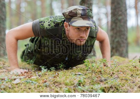 war, army, training and people concept - young soldier or ranger wearing military uniform doing push-ups in forest