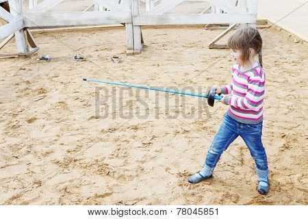 Pretty Little Happy Girl Standing On Sand With Blue Rapier Training For Fencing