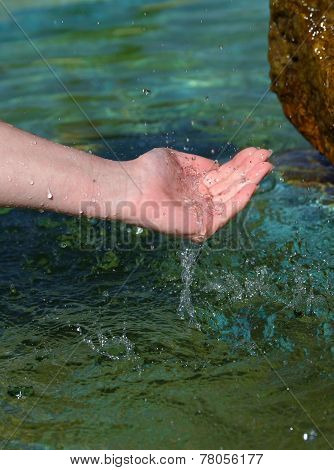 Beautiful woman hand in clear mountain water