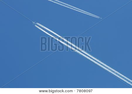 Flygande Airoplanes på den blå himlen lämnar vita linjer bakom