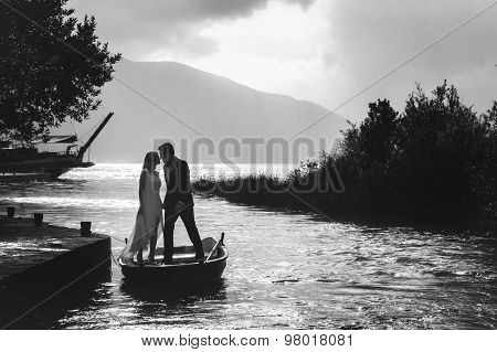 Stylish Young Bride And Groom Stand In Boat On Background Cloudy Sky Sea And Mountains Of Montenegro