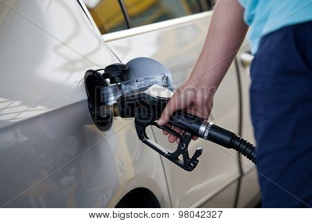 Silver car at gas station being filled with fuel