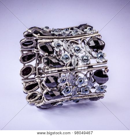 braclet with gems on color background.