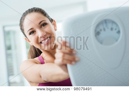 Happy Woman Showing A Scale