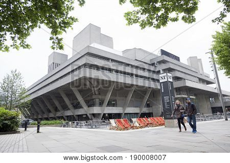 London United Kingdom 6 may 2017: couple walks on southbank of river thames in front of national theatre on overcast day in spring