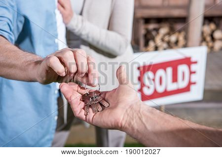 Close Up View Of Saleman Giving Keys Of House To New Owners