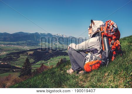 Woman backpacker traveler sits on the mountain hill with beautiful view on valley