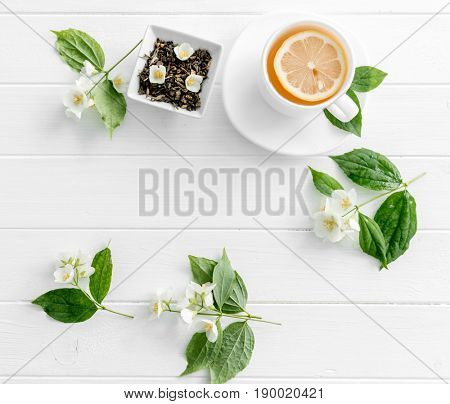 Teatime with jasmine green steaming tea, piece of lemon, jasmine flowers, space for text, topview
