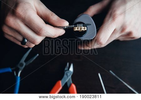 male master installs a coyle. Spiral for electronic evaporator and cigarette. Vape, vaping. Pliers, wire, fichral, coil, screwdriver