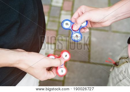 Close-up Two boyfriends tweens spinners on the street against each other Two fidget spinners