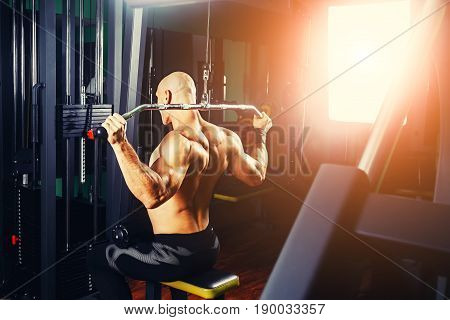 very power athletic guy bodybuilder, execute exercise with gym apparatus, on broadest muscle of back