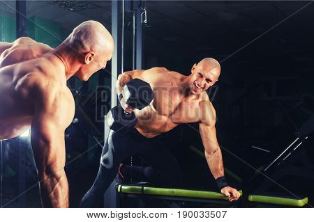very power athletic guy , execute exercise press with dumbbells, in sport hall