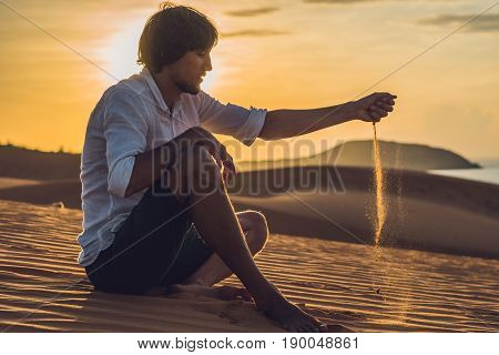 A Man Is Pouring Sand In The Desert. Sand Through The Fingers Of The Concept