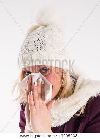 Portrait of a pretty woman in turtleneck sweaterand and scarf having flu. girl blowing nose standing over gray background and black and white with red accent