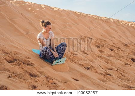 Young Woman Rolls On A Toboggan In The Sledge In The Desert