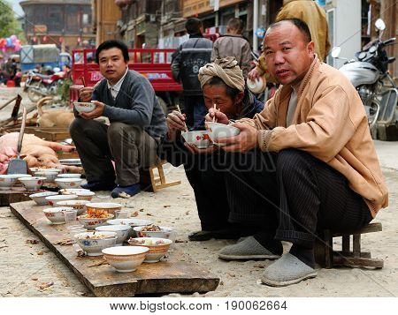 ZHAOXING CHINA - 11 NOVEMBER 2010: Residents of the Zhaoxing is a pretty Dong minority town eating on the High Street on the shared meal