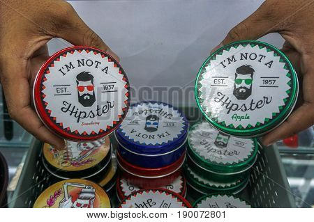 Labuan,Malaysia-May 26,2017:Man's hand holding the various kind of hair styling gel oil pomade at street market in Labuan,Malaysia.Pomade gives the user's hair a shiny & slick appearance.
