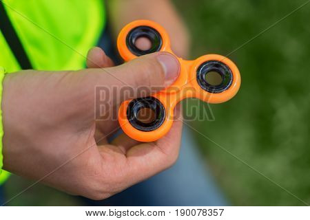 trendy fidget spinner - person holding orange fidget spinner in hand, close up view