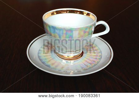 A white iridescent tea cup and saucer