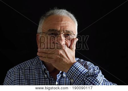 Man with hand in mouth on black background