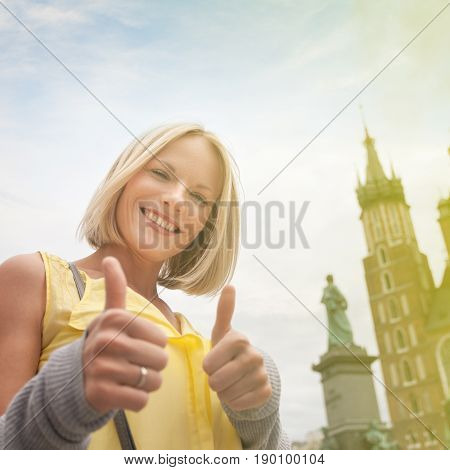 Female tourist in a yellow dress stands on a background of the church of St. Mary in Krakow. Basilica Mariacka. Krakow. Poland.