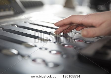 Female radio host using adusting volume at music mixer in radio studio