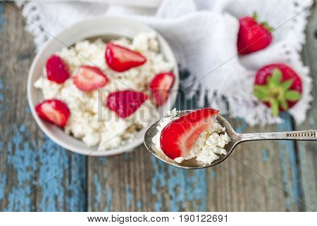 Spoon with cottage cheese and strawberries, close-up, top view