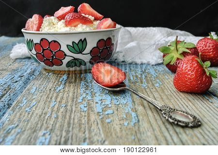 A plate of cottage cheese and strawberries on a wooden table