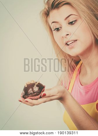 Diet sweets food concept. Woman holding delicious chocolate cupcake with peanut frosting about to take bite
