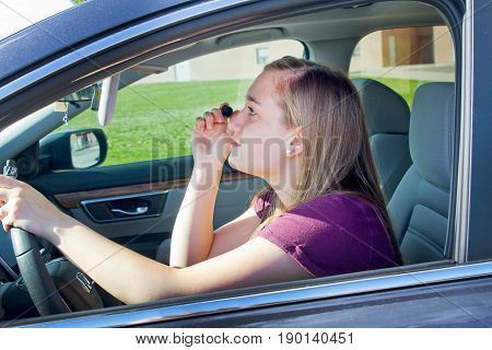 teenage girl putting on makeup while driving