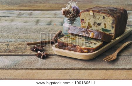 Homemade fruit cake on wood plate. Rum fruit cake with dried fruits made for Christmas celebration. Traditional homemade fruit cake for Christmas so delicious rich and moist on rustic wood table. Slice of delicious Christmas fruit cake.
