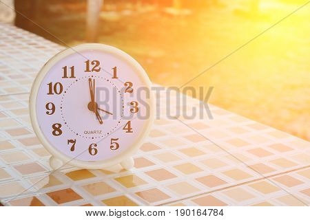 White clock at 5pm on the tiled floor and seashore background Freedom concept Sunshine effect Vintage tone