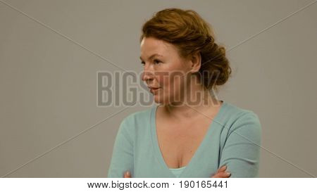 Mid aged female showing emotions of arrogance and despite. Foxy haired woman with despite and anger look in the studio close view. Toned footage.