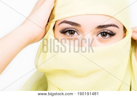 Closeup of beautiful young arabian woman in yellow hijab. Charm and beauty of the East
