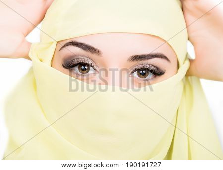 Closeup of beautiful young arabian woman in yellow hijab. Charm and beauty of the East