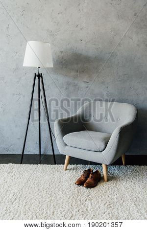 Leather Oxford Shoes On Carpet Near Textile Armchair And Lamp At Empty Room