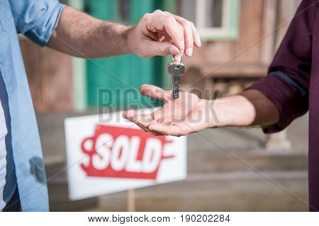 Cropped View Of Man Buying New House And Taking Keys, Sold Sign Behind
