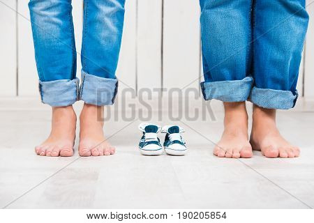 Waiting of baby. Pregnant woman, pregnancy, motherhood. Happy family. Mom's, Dad's and baby's bootees. Family look.