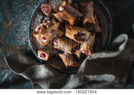 Cannoli on a tin plate, a gray napkin on a blue slate horizontal