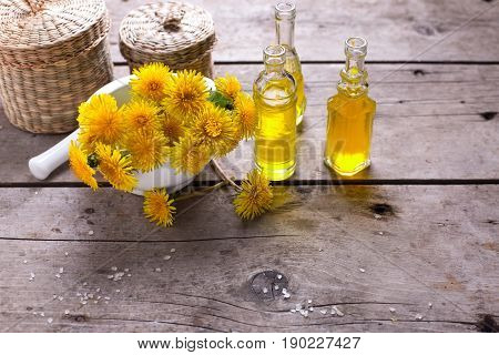 Fresh yellow flowers tussilago in mortar on wooden background. Wellness setting. Selective focus. Place for text.