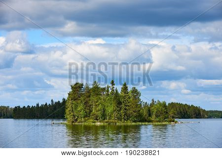Relaxing Finnish landscape with lake forest trees sky and reflected clouds