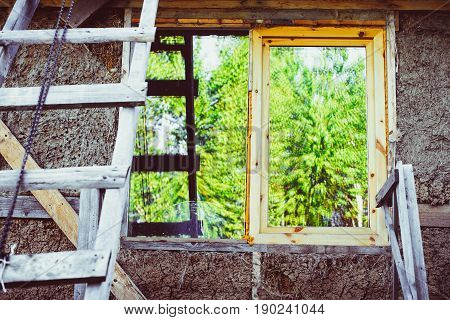 A new window in a new house. Unfinished balcony. Decorative plaster. Decorative tiles. roof construction. Urban house or building facade pattern. Rain gutter