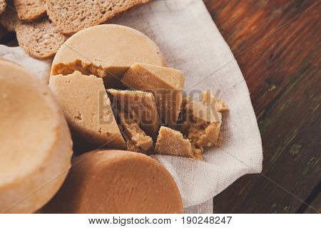 Norwegian homemade brown cheese brunost with crackers or crispbread on wooden desk, close-up, selective focus