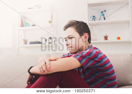 Unhappy lonely teenage boy at home, thinking about something, pubertal period, psychological problem. Lost in thoughts.